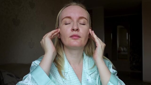 Adult woman touching facial wrinkles on forehead and between eyebrows. She does anti aging massage and considers botox injection.