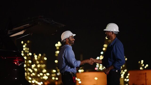 Engineer wear uniform and helmet stand workplace hand holding tablet and laptop computer, survey inspection team work plant site to work with night lights oil refinery background.	