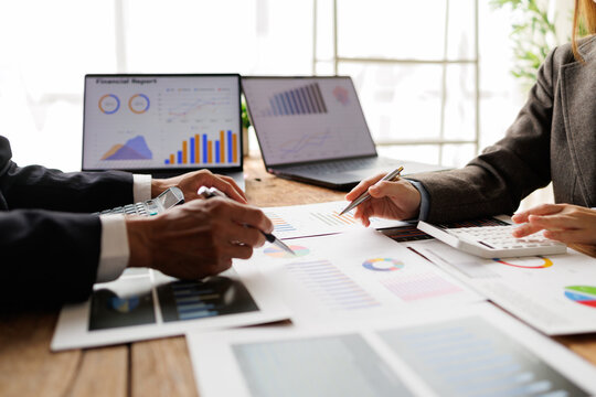 Business people analyzing financial reports, reviewing data charts on paper documents and laptop screens, calculating investment strategy and accounting with teamwork collaboration