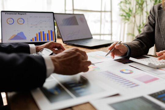 Business professionals analyzing financial reports, reviewing marketing strategy, and collaborating on data analytics, discussing company growth in an office meeting
