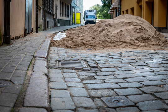 Large Sand Pile Blocks a Narrow Cobblestone Street During Construction