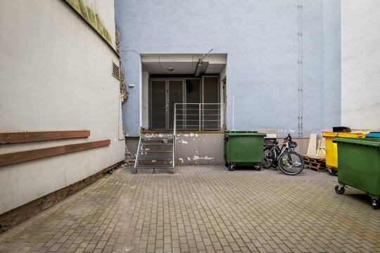 Colorful Waste Bins and Bicycles Beside an Urban Service Entrance