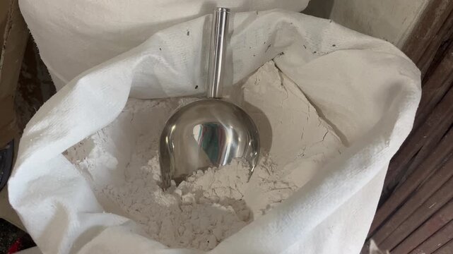 Close up shot of organic white flour or starch inside a sack with a stainless steel scoop