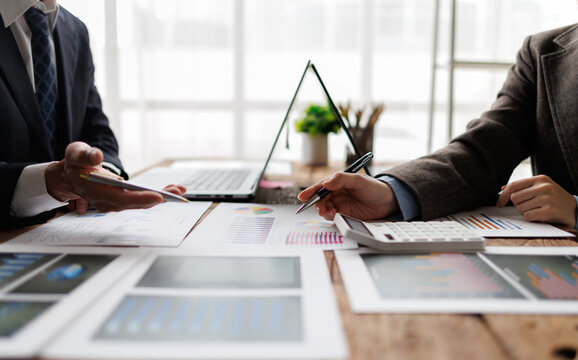 Business professionals discussing financial data, analyzing market trends, collaborating on investment strategies, and planning company growth during an office meeting
