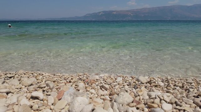 Static close up shot of clear turquoise water on pebbled beaches of Karaburun