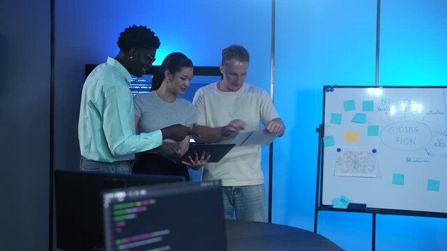 Diverse tech startup IT teams meeting in modern office. Asian female and male software developers analyzing coding innovation on laptop. Corporate technology teamwork and business development concept