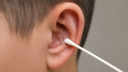 Naklejka premium Close up of cleaning a child's ear with a cotton swab, hygiene and ear care concept