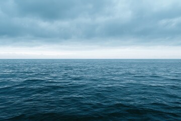 Obraz premium Cloudy Blue Horizon Over a Calm Sea: Seascape under an Overcast Sky