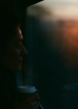 Close-up of a person's face, holding a cup of coffee. the person is facing away from the camera, and their face is partially obscured by the shadow of the cup.
