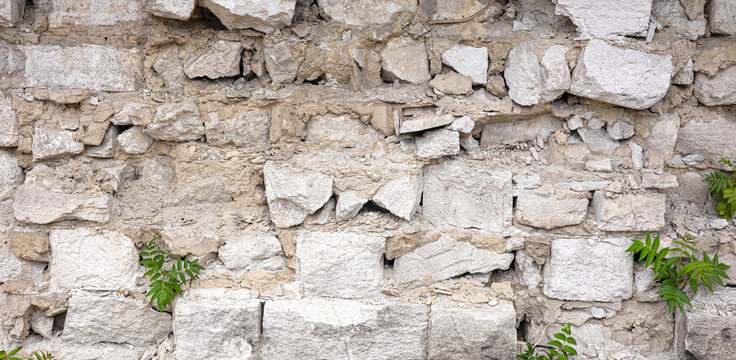 Old stone wall with crumbling rough limestone blocks