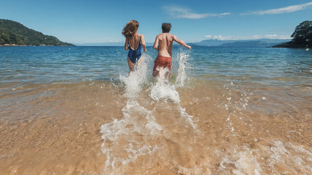 Young couple of man and woman run into the tropical sea