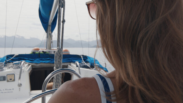 Woman sailing alone the small sailing boat in the calm sea during nice sunny day.