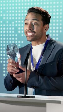 Business, man and award on podium at seminar, nomination and thank you speech for recognition. Smile, person and speaker at conference with trophy, corporate excellence and outstanding performance