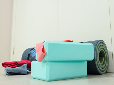 Assorted Yoga And Fitness Gear Rests On Floor Near White Wall, Including Rolled Mats, Foam Blocks, Resistance Band, Towels, And Water Bottle, Creating Calm Minimal Wellness, With Yoga, Fitness