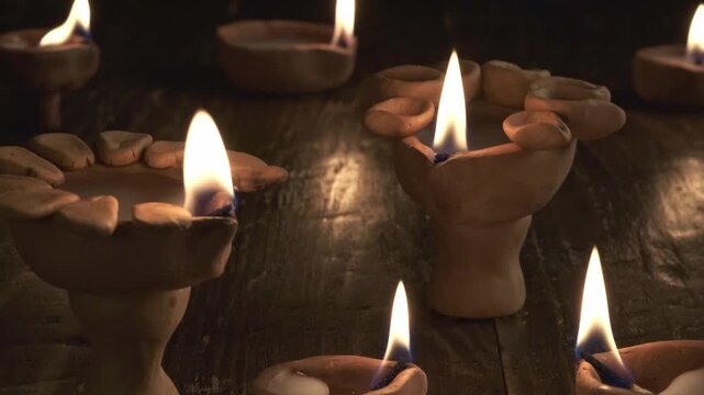 Diwali diya lamps with softly moving flames and shallow depth of field