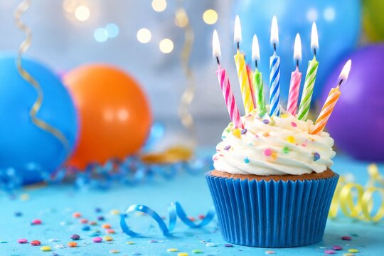 Birthday cupcake with colorful candles and balloons