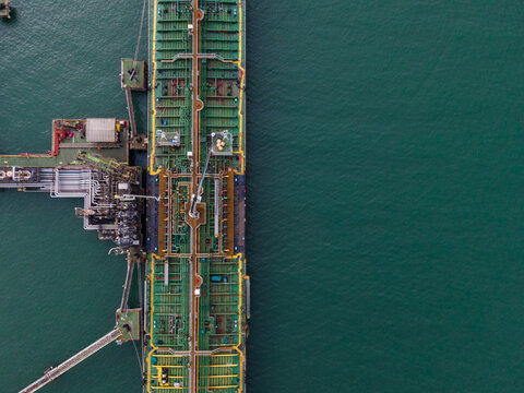 Aerial view of a large industrial oil tanker ship docked at a terminal pier in the sea, Cilacap, Central Java, Indonesia.