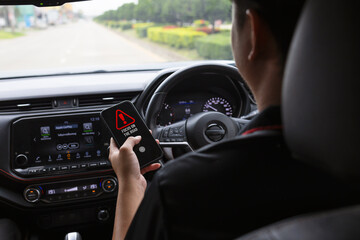 Driver holding a smartphone while driving, illustrating distracted driving and road safety awareness © memorystockphoto