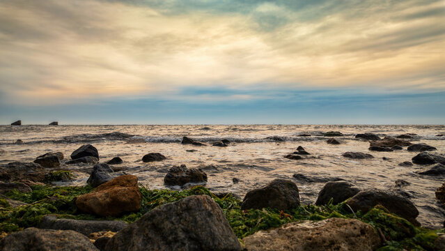 Rocky seashore with waves cloudy sky