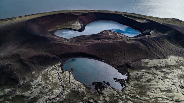 Aerial view of Litlisjor volcanic crater lake with its distinct dark basaltic slopes and surrounding moss-covered lava fields in the highlands of Rangarthing ytra, Iceland.