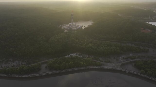 Aerial drone view of Mui Ca Mau National Park in Dat Mui, Ca Mau, Vietnam, featuring the national flagpole and coordinate marker surrounded by sunlit mangrove forests.