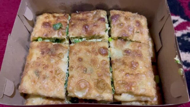 Indonesian savory fried pancake known as Martabak Telur served in a takeaway cardboard box