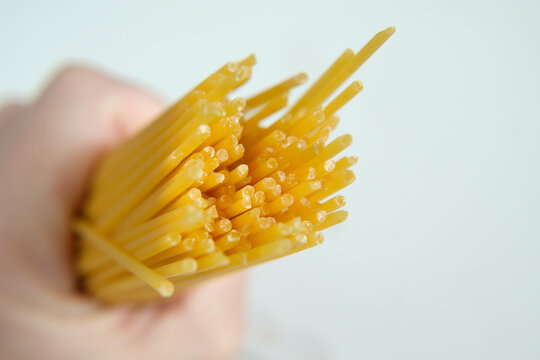 Hand holding raw spaghetti pasta noodles for cooking