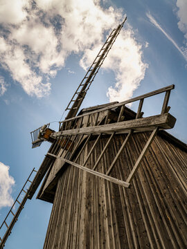 Rustic Wooden Windmill With Sunlit Sails Against A Clear Blue Sky In Countryside