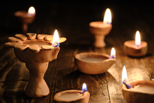 Diwali diya lamps arranged at different heights against a black background