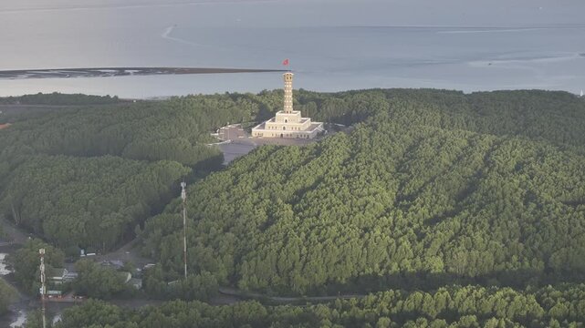 Aerial drone view of Mui Ca Mau National Park in Dat Mui, Ca Mau, Vietnam, featuring the national flagpole and coordinate marker surrounded by sunlit mangrove forests.