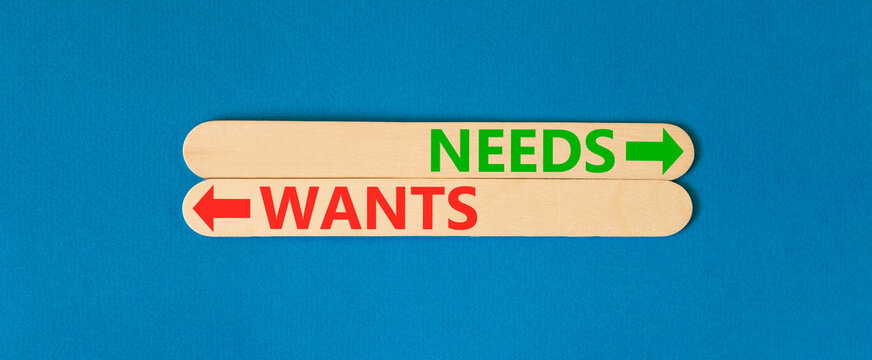 Needs instead wants words symbol. Concept words Needs Wants on beautiful wooden sticks. Beautiful blue background. Business psychology needs or wants concept. Copy space.