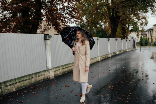 Young woman walking alone with umbrella in autumn rain