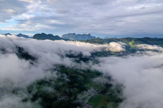 Aerial view of the mountainous landscape of the Austrian Alps, with clouds rolling over green valleys and rugged peaks Saalbach-Hinterglemm, Salzburg, Austria.