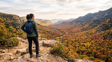 Obraz premium Female hiker admiring autumn valley view from mountain overlook during fall season travel adventure