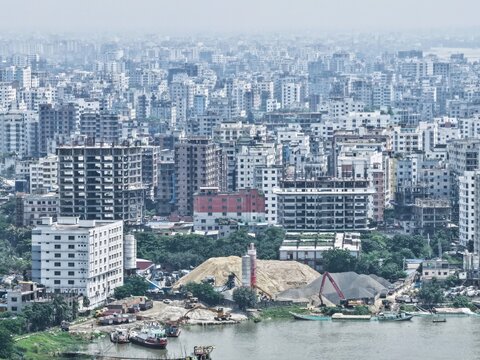 Aerial view of the Gabtoli area featuring construction sites, sand piles, and industrial riverfront activity set against dense urban buildings in Dhaka, Dhaka Division, Bangladesh.