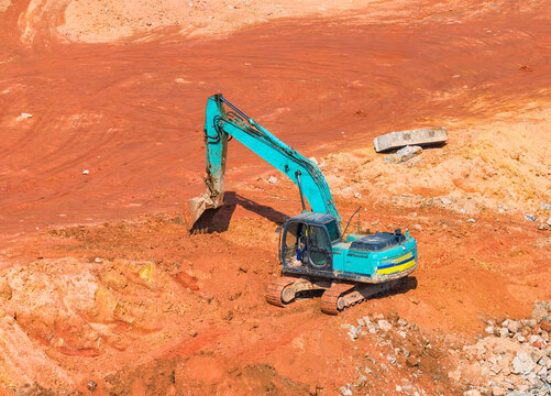 Excavator on earthmoving at construction site, aerial view.