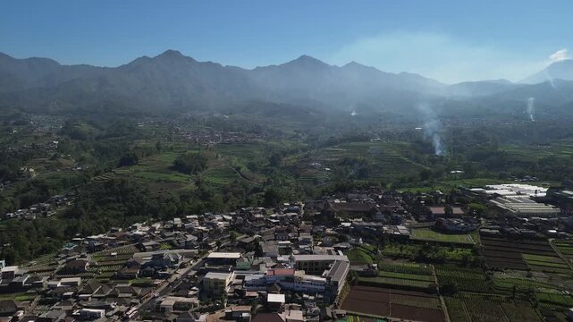 Aerial drone footage of rural village and green vegetable farmland with Mount Panderman background in Pujon, Malang