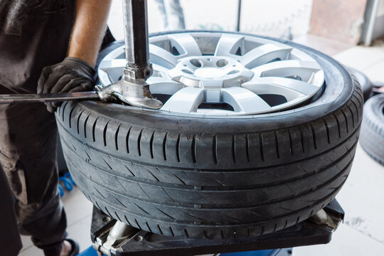 Tire replacement mechanic installs tire on alloy wheel with mounting machine, professional garage service for vehicle maintenance, rim protection and driving safety.