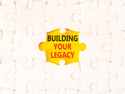 Building your legacy words symbol. Concept words Building your legacy on beautiful white puzzle. Beautiful yellow background. Business building your legacy concept. Copy space.
