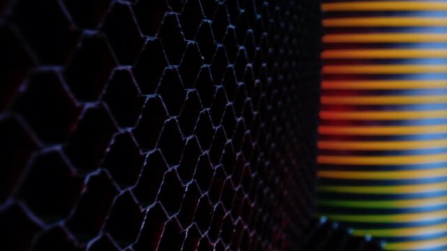 Oblique close-up of hexagonal honeycomb grid filling left side while blurred horizontal bands create warm gradient across right side, combining cool rim light, dark contrast, and abstract texture