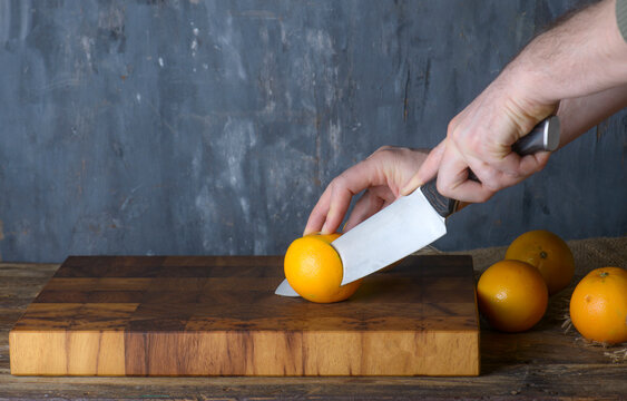 Chef Slicing Fresh Oranges on Wooden Board