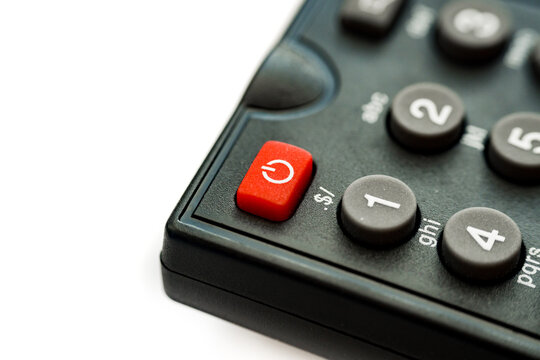 Macro close-up of a black remote keypad with a prominent red power button isolated on white background. Start, reboot, power on and off concept.