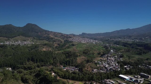 Aerial drone footage of rural village and green vegetable farmland with Mount Panderman background in Pujon, Malang