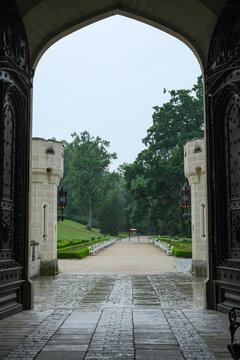 Professional architecture photography of Hluboka nad Vltavou castle gate. Famous romantic landmark with paved entryway leading to lush gardens for European travel catalog.
