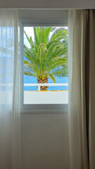 Fototapeta premium Hotel window overlooking the sea with palm tree