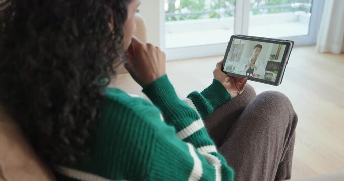 After call, adult African American woman with tablet raising bottle red cap showing doctor on couch
