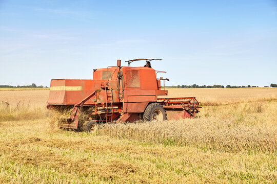 Photo of a combine harvesting wheat on a sunny summer day.