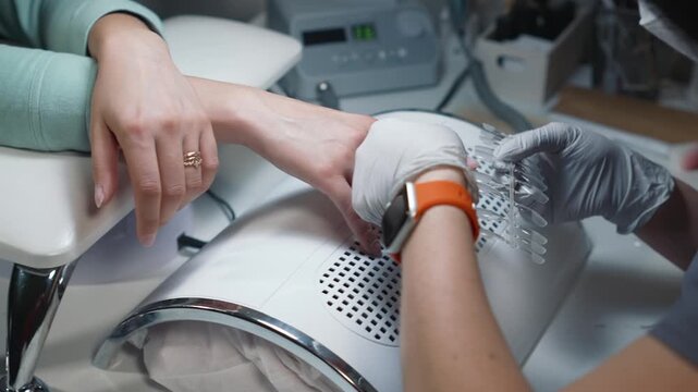Manicure technician selects nail tips by natural nail width in beauty salon for accurate and precise nail extension preparation