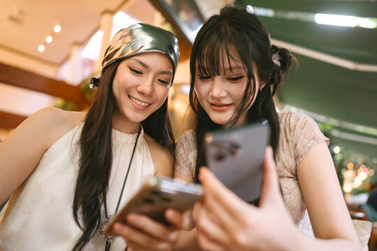 Happiness two young asian women using cell phone hanging out with friends shared experience Bangkok trip moment