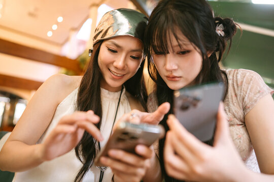 Happiness two young asian women using cell phone hanging out with friends shared experience Bangkok trip moment
